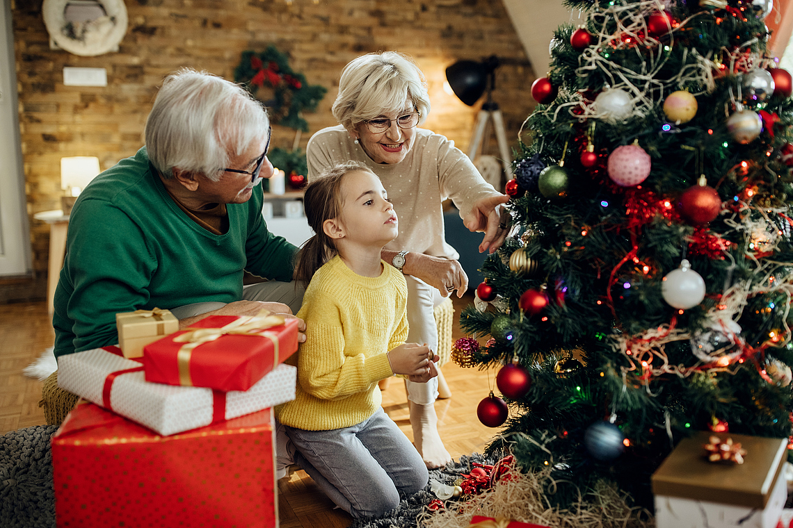 little-girl-her-grandparents-decorating-christmas-tree-together-home